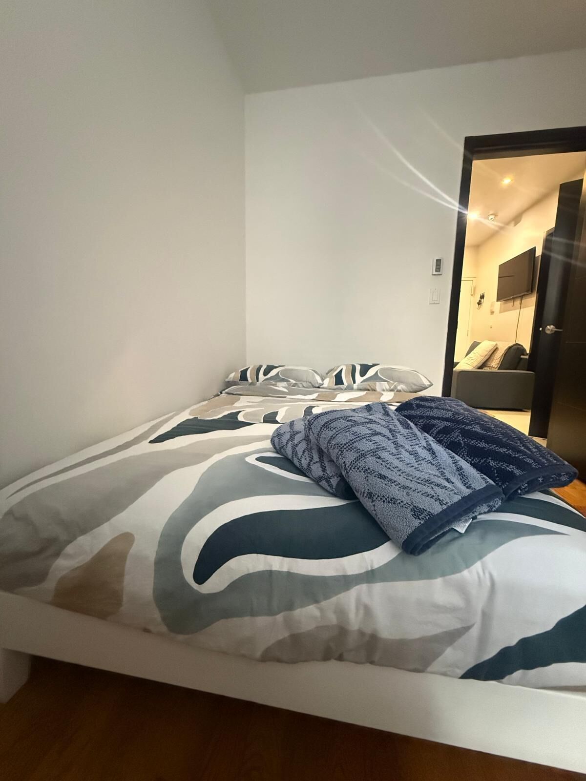 Una cama con una colcha estampada, una manta doblada y almohadas.