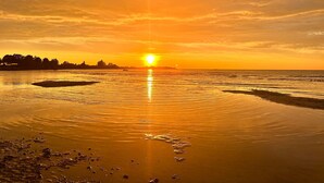 Ein Sonnenuntergang über ruhigem Wasser mit einer fernen Küstenlinie.