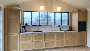 Eine Küche mit Holzausstattung, einem großen Fenster und einem schwarzen Kühlschrank.