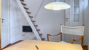 Een kamer met een houten tafel, een witte stoel, een witte deur, een witte muur, een wit plafond en een witte vloer.