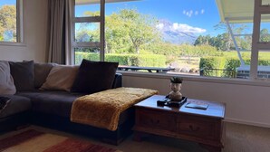 Un salón con sofá, una mesa de centro y vista a un paisaje montañoso a través de amplios ventanales.