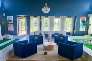 A room with blue upholstered seating, a round wooden table, and a chandelier.
