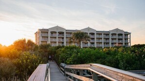 Un hôtel doté d’une promenade en bois menant à un bâtiment agrémenté de nombreux balcons.