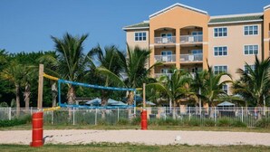 Un hôtel à la structure de deux étages, doté d’un espace extérieur clôturé avec un filet de volley-ball et de palmiers.