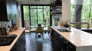 Une cuisine moderne dotée d’un grand îlot central, d’un coin repas et offrant une vue sur l’extérieur.