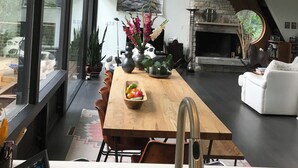Une cuisine moderne avec une table en bois, un four encastré et une grande fenêtre donnant sur un jardin.