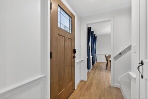 Ein Flur mit einer Holztür, weißen Wänden und einem Teppichgesteckten Treppenhaus.