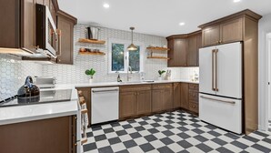 Una cocina moderna con armarios de madera, un refrigerador blanco y un piso a cuadros blanco y negro.