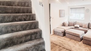 Eine Treppe führt zu einem Wohnbereich mit einem Ecksofa und einem Teppich.
