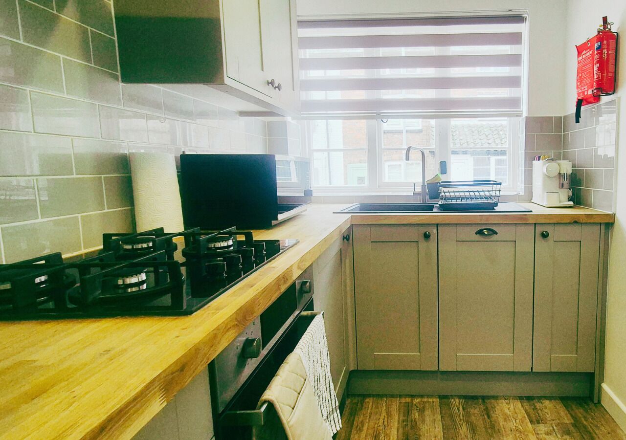A kitchen with a gas stove, oven, and wooden countertop.