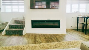 Ein Wohnzimmer mit Kamin, Treppe und Blick ins Freie.