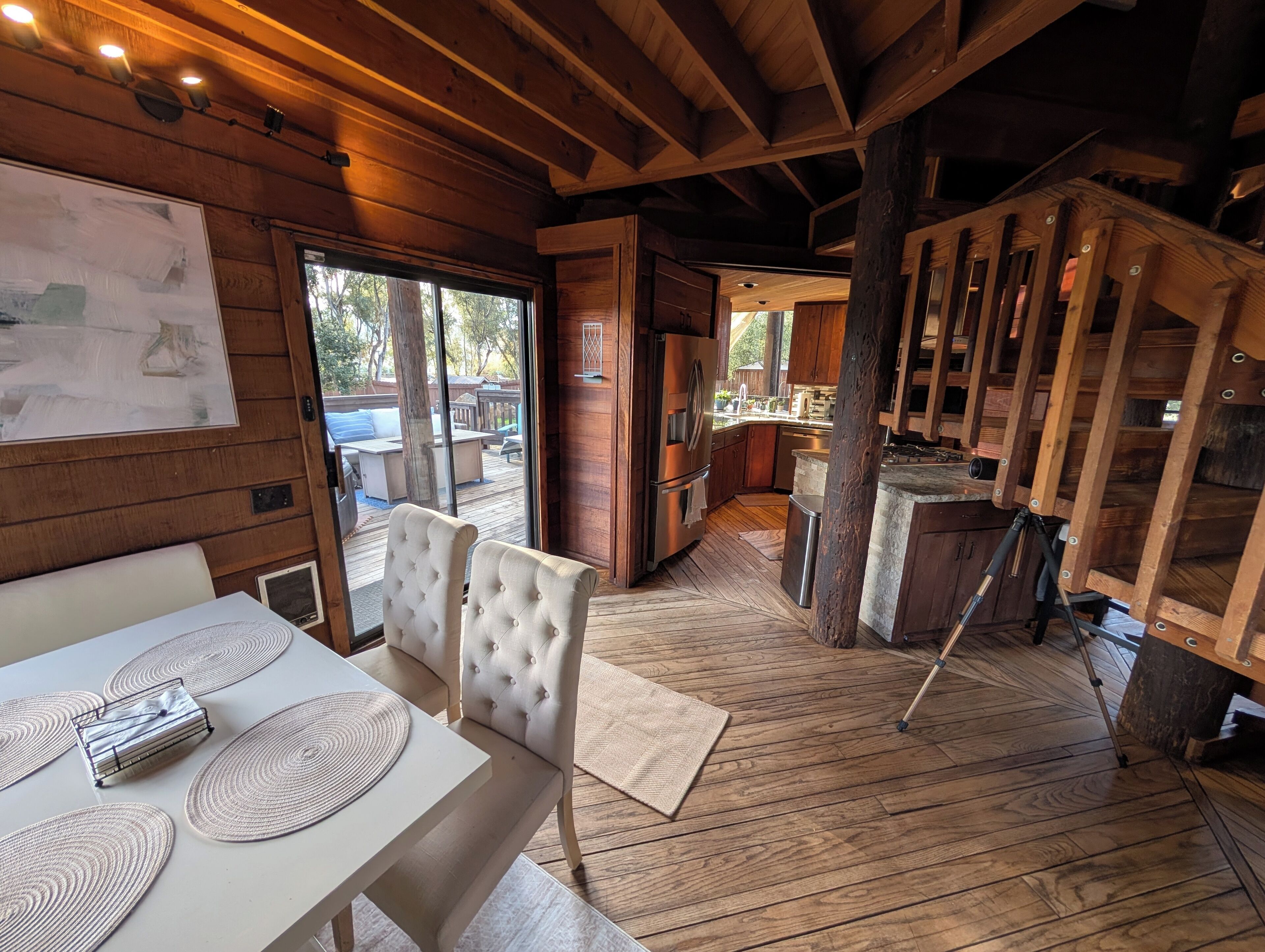 A wooden interior with a dining area, kitchen, and a staircase.