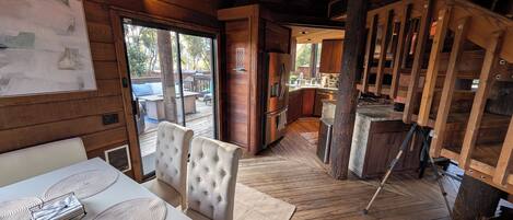 A wooden interior with a dining area, kitchen, and a staircase.