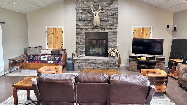 A living room with a stone fireplace, leather sofa, TV, and wooden accents. - Family Retreat with pool table and double bunks. (Bethany)