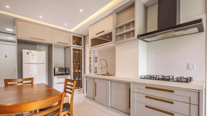 A modern kitchen with integrated appliances, a dining area with a wooden table and chairs, and built-in shelving. - Your Complete Stay Just Minutes From the sea in BC Stls (Balneário Camboriú)