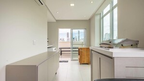 A modern kitchen with a city view, a sliding glass door leading to a balcony, and a large window providing natural light. - Your Complete Stay Just Minutes From the sea in BC Stls (Balneário Camboriú)