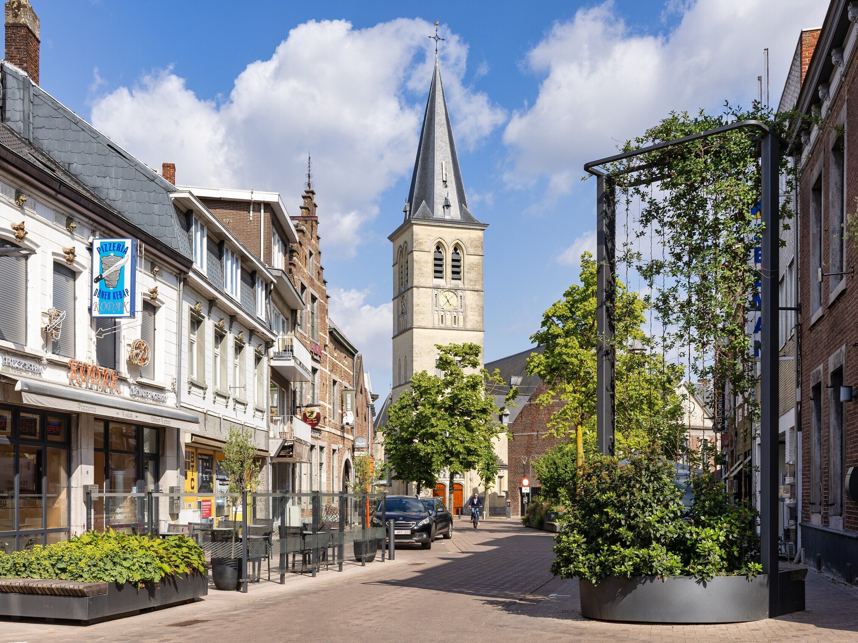 A street with buildings, a clock tower, and a pizzeria sign.