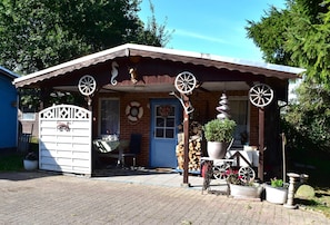 Una construcción rústica de madera con un porche, una cabeza de venado decorativa y un reloj.