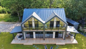 A two-story house with a large balcony, a deck, and a stone pathway leading to two lounge chairs. - Cozy home in Sianowo with house sea view (Sianowo)