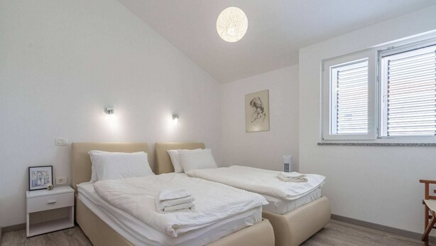 A double room with two beds, bedside tables, a wall-mounted light, a window with blinds, and a framed picture on the wall. - Quiet Privlaka Retreat With sea Views (Privlaka)