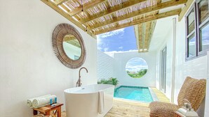 Une salle de bain moderne avec une baignoire sur pieds, un miroir rond et une vue sur une piscine.