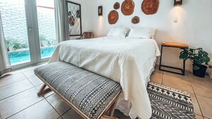 Une chambre avec un lit, un banc et une vue sur une piscine.