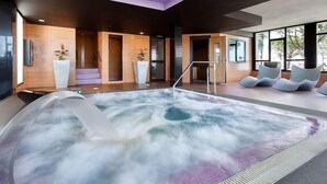 A modern spa area with a hot tub, wooden walls, and a view of trees. - Riu Chiclana (Chiclana de la Frontera)