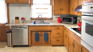 Una cocina con gabinetes de madera, lavavajillas de acero inoxidable, microondas y horno.