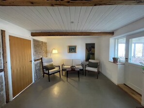 Et værelse med træloft, hvid dør, stenvæg og et vindue med udsigt.