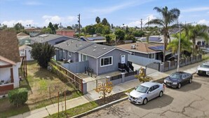 Un quartier résidentiel avec des maisons, une allée d’accès fermée par un portail et des voitures garées.
