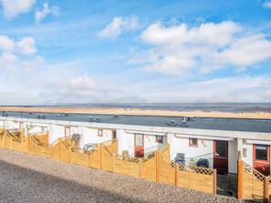 A row of white buildings with numbered doors, a gravel path, and a view of the beach. - 4 Person Holiday Home in Romo (Rømø)