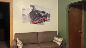 Un salon avec un canapé marron, un mur vert et une porte.