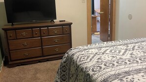 Une chambre à coucher avec un lit, une commode et un téléviseur.