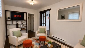 A living room with two white sofas, a coffee table, a TV displaying 'NETFLIX,' and a patterned rug. - Northeast ABQ Home Near State Fair I40 with Huge back yard and Fire Pit (Albuquerque)