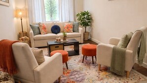A living room with a sofa, two armchairs, a coffee table, a lamp, a plant, and a window with blinds. - Northeast ABQ Home Near State Fair I40 with Huge back yard and Fire Pit (Albuquerque)
