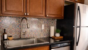A kitchen with wooden cabinets, a stainless steel refrigerator, a dishwasher, and a tiled backsplash. - Northeast ABQ Home Near State Fair I40 with Huge back yard and Fire Pit (Albuquerque)