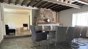 A dining area with a stone wall, a wooden table, and grey chairs. - Holiday Home in Ruisseau de Vaux (Villers-le-Bouillet)