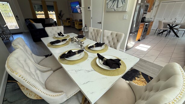 A dining area with a marble table set for four, surrounded by tufted chairs with gold studs. - Vibrant modern boutique/w stunning lap pool (Sarasota)