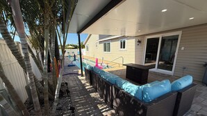 A patio area with a pool, outdoor seating, and a covered section. - Vibrant modern boutique/w stunning lap pool (Sarasota)