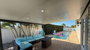 An outdoor patio with a pool, a blue sofa, and a table. - Vibrant modern boutique/w stunning lap pool (Sarasota)