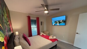 A modern bedroom with a bed, a ceiling fan, a TV on the wall, and a window with curtains. - Vibrant modern boutique/w stunning lap pool (Sarasota)
