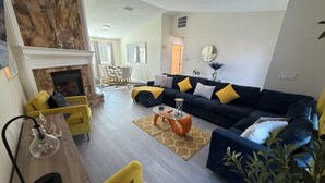 A modern living room with a sectional sofa, yellow chairs, a fireplace, and a dining area with a table and chairs. - Vibrant modern boutique/w stunning lap pool (Sarasota)