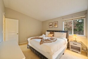 A bedroom with a bed, bedside table, lamp, and a window with a view. - Chic 3BR Home | Foosball • Great Location@Bellevue (Bellevue)