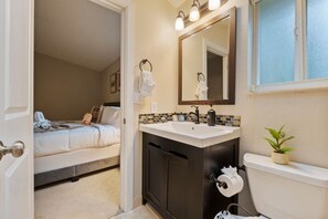 A hotel bathroom with a sink, mirror, and toilet. - Chic 3BR Home | Foosball • Great Location@Bellevue (Bellevue)