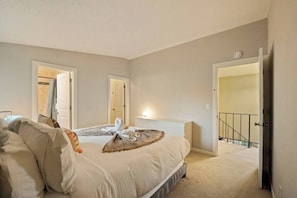 Ein Schlafzimmer mit Bett, Nachttischen und einer Tür, die auf einen Balkon führt.