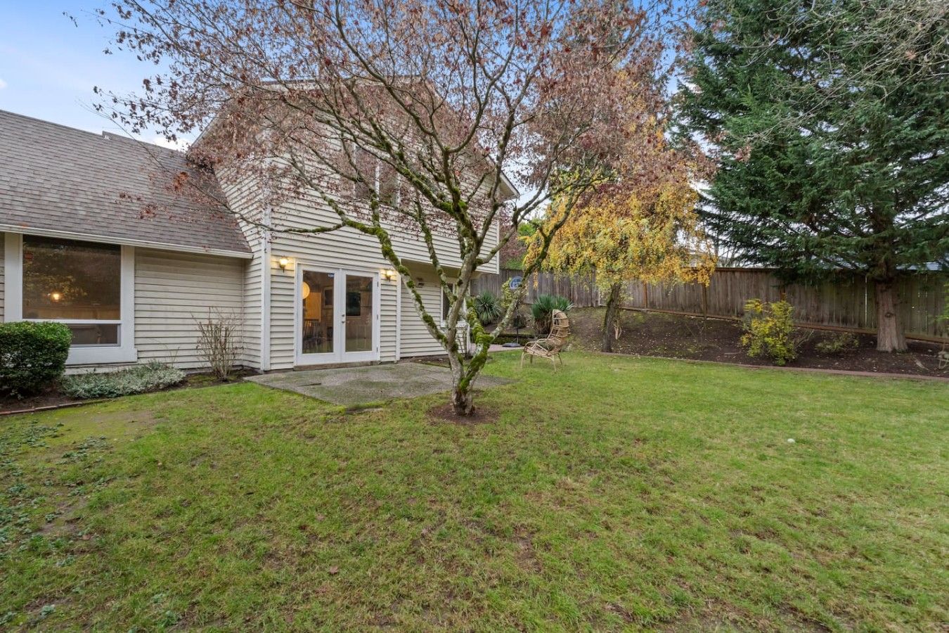 A residential property with a well-maintained lawn, a detached garage, and a wooden fence.