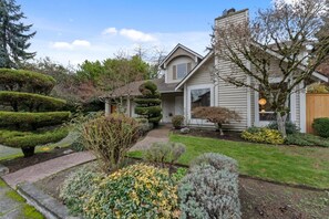 A residential property with a well-maintained garden, a two-story house, and a visible chimney. - Chic 3BR Home | Foosball • Great Location@Bellevue (Bellevue)