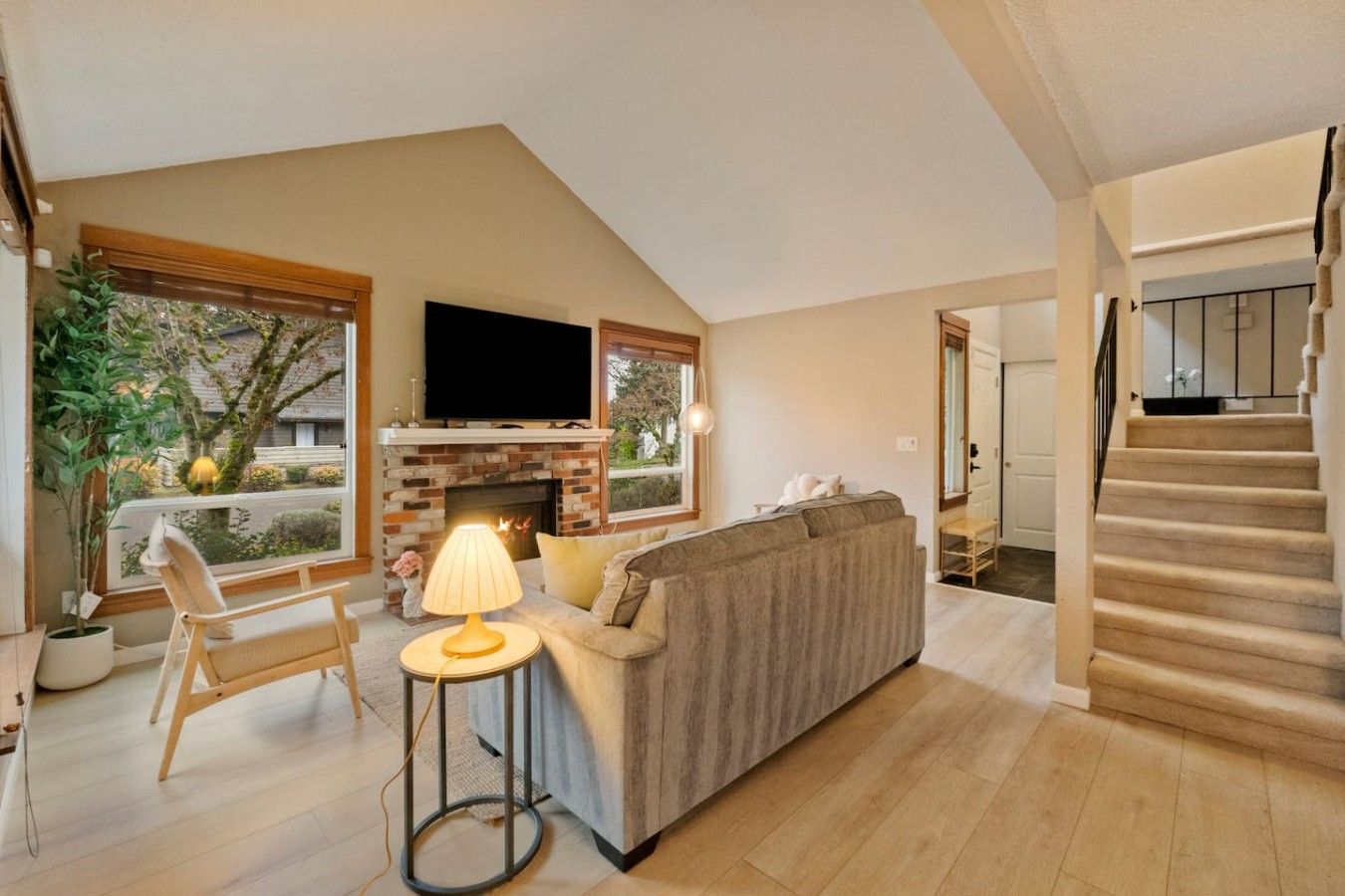 A living room with a fireplace, a sofa, a TV, and a staircase.