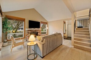Ein Wohnzimmer mit Kamin, einer Couch, einem Fernseher und einer Treppe.