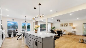 A modern kitchen with a central island, a dining area with chairs, a sofa, and a view of the outdoors. - Spacious 3B2B Upper unit breathtaking lake views (Auburn)